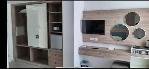 a bathroom with a mirror and a tv on a wall at Karousos Beach Rooms in Ayia Napa