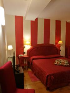 ルッカにあるHotel La Lunaの赤と白のストライプの壁とベッドが備わるベッドルーム1室