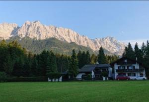 a house in a field with mountains in the background at Gästehaus Lehnerer Grainau in Grainau