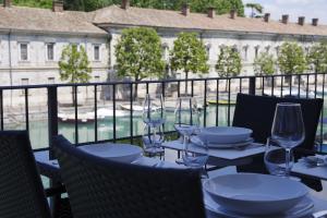 una mesa con copas de vino y platos en el balcón en Time To Relax La Terrazza sul Lago en Peschiera del Garda