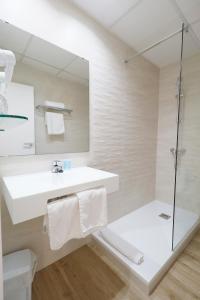 a white bathroom with a sink and a shower at Martinez Apartments in Palmanova