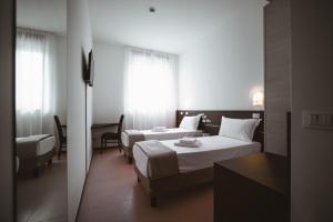 pokój hotelowy z 2 łóżkami i oknem w obiekcie Albergo Commercio w Palmanovej