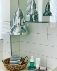 a bathroom with a basket of towels and two lights at Heideviertel in Bispingen
