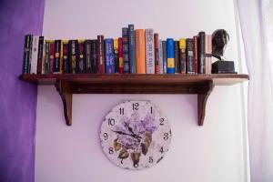 a shelf with books and a clock on a wall at B&b Cefalù in Cefalù