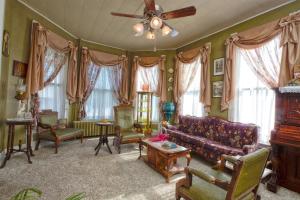 a living room with a couch and chairs and a ceiling fan at The Victorian on Main in Fairfield
