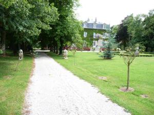 a gravel path in a park with a house in the background at Manoir de la Marjolaine in Cabourg