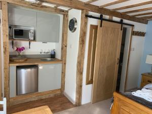 una pequeña cocina con fregadero y microondas en Newton Farmhouse, en Whiteparish