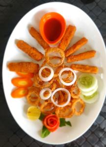 a plate of food with onion rings and vegetables at Elephant Garden Hotel and Resort Pvt Ltd in Kanchanpur