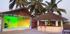 un magasin avec un bâtiment vert et jaune planté de palmiers dans l'établissement Elephant Garden Hotel and Resort Pvt Ltd, à Kanchanpur