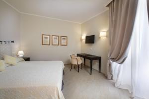 a room with a bed, chair, table and lamp at Hotel Villa Margherita in Golfo Aranci