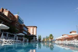 una piscina con sedie bianche e ombrelloni di Hotel Granada Palace a Monachil