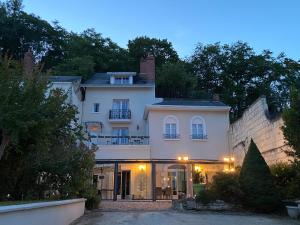 uma grande casa branca com uma varanda em cima em Les Rives du Cher - Chambres d'hôtes em Montrichard