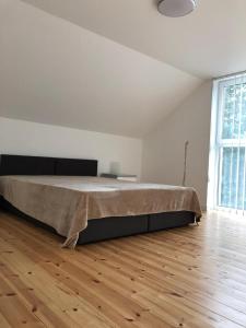 a large bed in a white room with a wooden floor at Morskie Wzgórze Apartamenty in Mechelinki