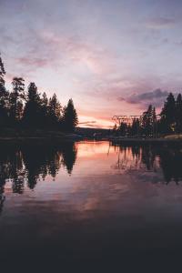 una puesta de sol sobre un cuerpo de agua con árboles en Noon Lodge, en Big Bear Lake