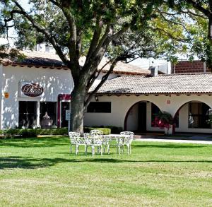 a table and chairs under a tree next to a building at Hotel Sand&acute;s San Luis in San Luis Potos&iacute;