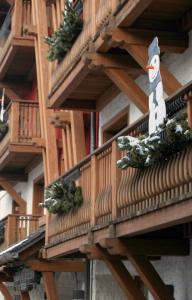 un balcón de madera con plantas de Navidad y un muñeco de nieve. en Hotel Belmonte, en Roana