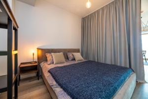 a bedroom with a large bed with a blue blanket at Modern spacious studio w/ Sea Views in Klaipėda