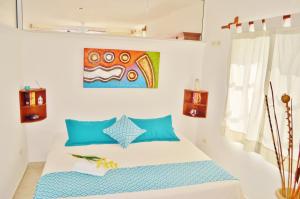 Un dormitorio con una cama con almohadas azules y una pintura en Corales Suites, en Puerto Morelos