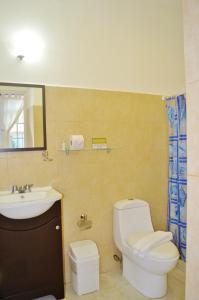 a bathroom with a white toilet and a sink at Corales Suites in Puerto Morelos