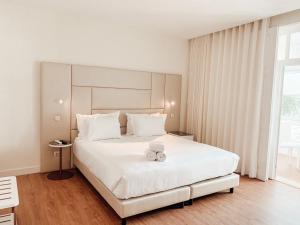 a bedroom with a large white bed with a towel on it at Le Premier Lisbon Suites in Lisbon