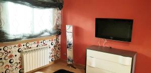ein Wohnzimmer mit einem Flachbild-TV an einer roten Wand in der Unterkunft Piso en Vigo 150m2 Hasta 7 huéspedes in Vigo
