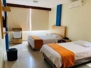 Habitación de hotel con 2 camas y TV en San Francisco Apart Hotel en Guayaquil