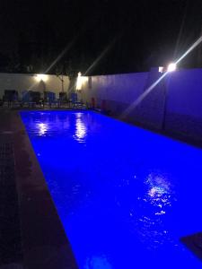 a swimming pool lit up blue at night at Too Many Suites in Saidia 