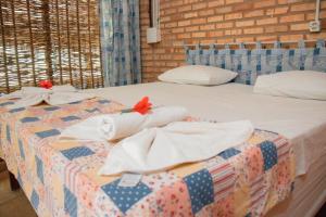 a bed with white towels and red flowers on it at Ocas do Índio Hotel Spa in Beberibe