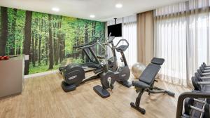 una sala de fitness con equipamiento de ejercicio y un mural en la pared en Sercotel Cornellà Barcelona en Cornellà de Llobregat