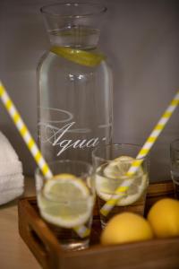 Una botella de limonada con dos vasos y limones en una bandeja de madera. en Hotel Zur Burg Sternberg en Extertal