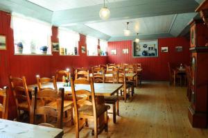 a dining room with red walls and wooden tables and chairs at Ullensvang Gjesteheim in Lofthus