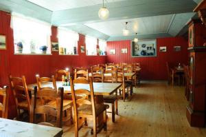 una sala da pranzo con pareti rosse e tavoli e sedie in legno di Ullensvang Gjesteheim a Lofthus