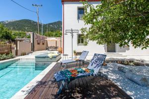 a pair of chairs sitting on a deck next to a swimming pool at Villa Skyphos in Ammoudari