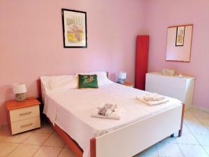 um quarto com uma cama branca e paredes cor-de-rosa em Villetta a Trebisacce con vista mare em Trebisacce