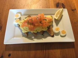 un plato blanco con un sándwich y huevos y una rodaja de limón en Catesby Barn Farm B&B en Daventry