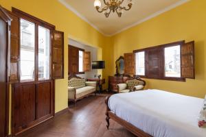a bedroom with yellow walls and a bed and windows at HomeForGuest NEW Duplex with Rooftop next to Arucas Cathedral in Arucas