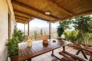eine Terrasse mit einem Holztisch auf dem Balkon in der Unterkunft Serenity View - traditional village apartment in Kousés
