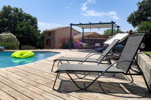 une paire de chaises assises sur une terrasse à côté d'une piscine dans l'établissement B&B Arghjola, à Porto-Vecchio
