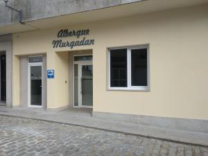 帕德隆Albergue & Rooms Murgadán的一栋白色建筑，侧面有一块招牌