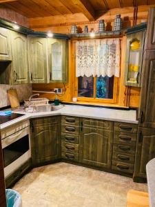 eine Küche mit Holzschränken, einem Waschbecken und einem Fenster in der Unterkunft Domek letniskowy Grodek in Gmina Gródek nad Dunajcem