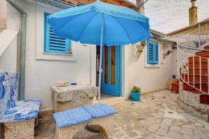 a blue umbrella and a table and a chair and a table and a table sidx at Apartments Kaštel in Veli Lošinj