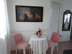 a table with pink chairs and a vase of flowers on it at Rent! Monthly or More in San Juan