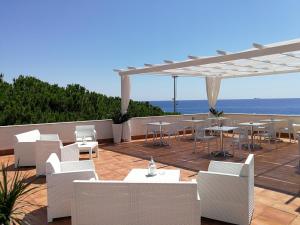 a patio with white tables and chairs and the ocean at B&B Il Mare degli Dei in Letojanni
