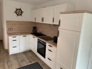 a white kitchen with white cabinets and a sink at Quartier Usedom in Ostseebad Karlshagen