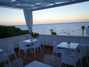 un patio con tavoli, sedie e vista sull'oceano di B&B Il Mare degli Dei a Letoianni