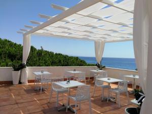 a patio with tables and chairs and the ocean at B&B Il Mare degli Dei in Letojanni
