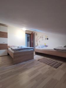 two beds in a large room with wooden floors at Guest accommodation house Greta in Tribunj