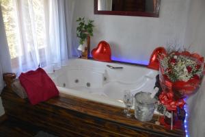 uma banheira na casa de banho com uma decoração de coração vermelho em Pousada Recanto Vale da Serra Chales em São Francisco de Paula