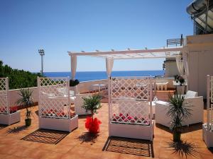 a patio with a white pergola and flowers at B&B Il Mare degli Dei in Letojanni