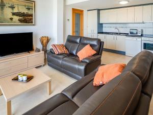 a living room with a leather couch and a tv at Comfortable Apartment in L Eucaliptus with Swimming Pool in Deltebre